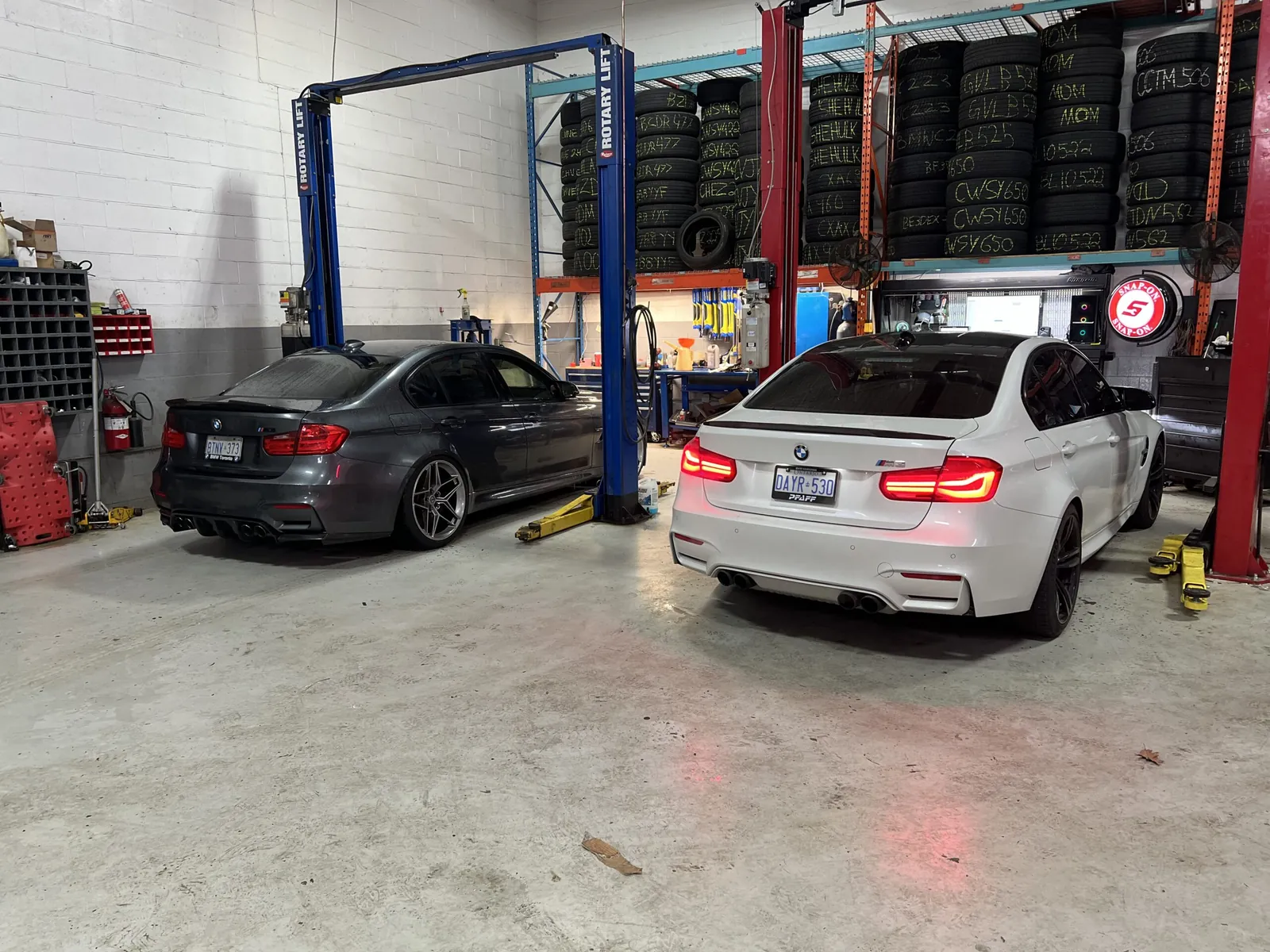 Two BMWs in the service bay, with tire racks behind